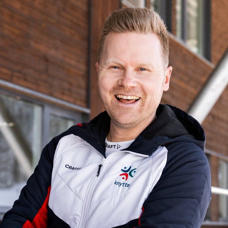 Emil Hauge i Knytte-jakke foran tømmerveggen