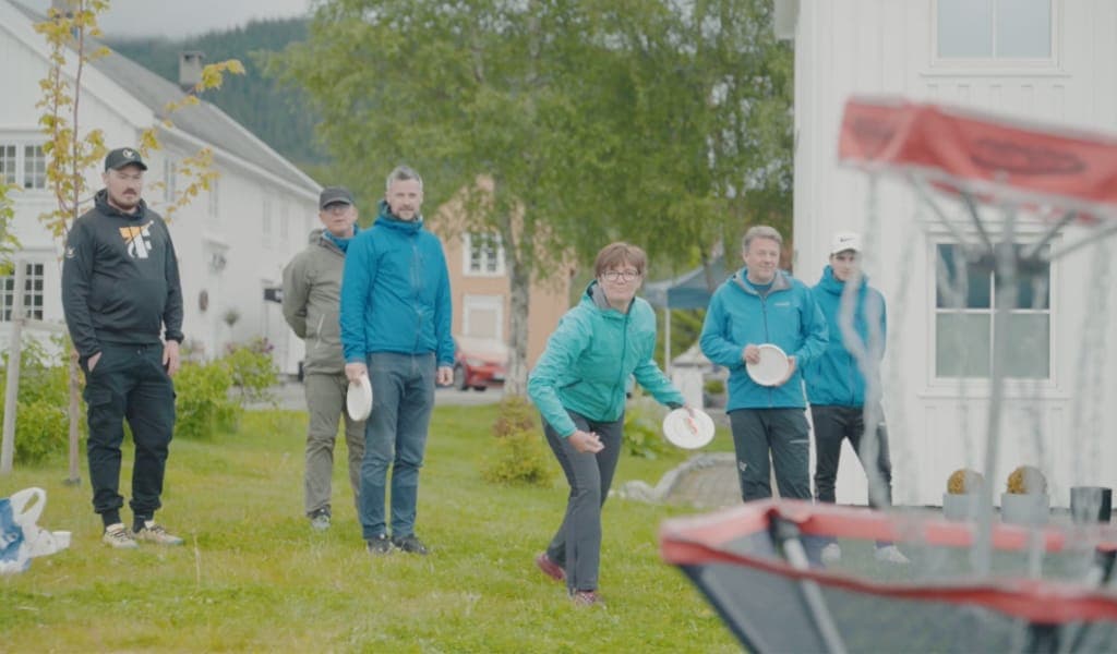 Medlem kaster frisbee mot kurven mens resten av gruppa venter på tur